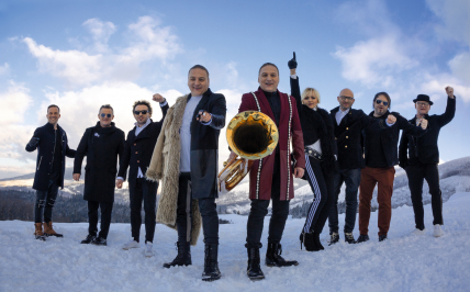 Grupa ludzi z instrumentami muzycznymi pozuje na zaśnieżonej łące