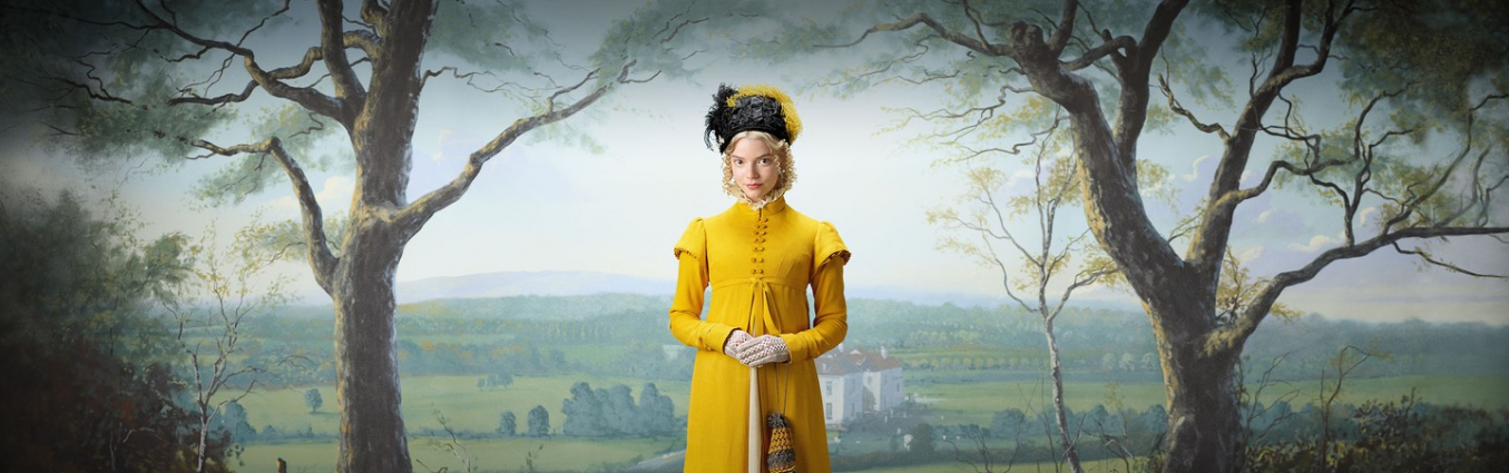 Kobieta w żółtej sukience trzyma w rękach parasol. Na głowie ma wielki kapelusz