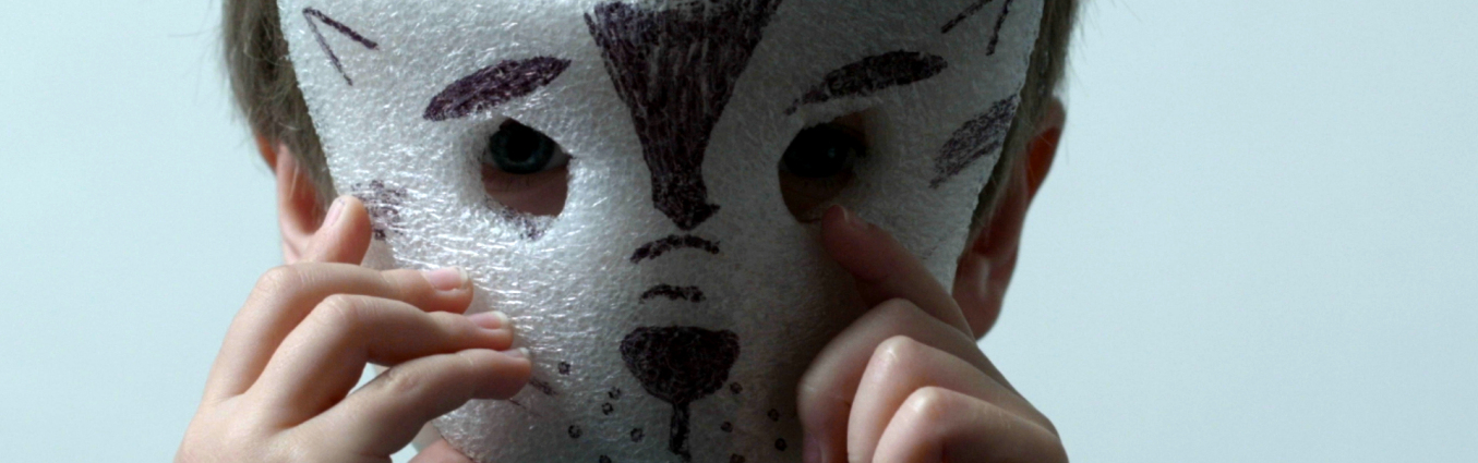 Chłopiec zasłaniający maską psa wykonaną ze steropianu