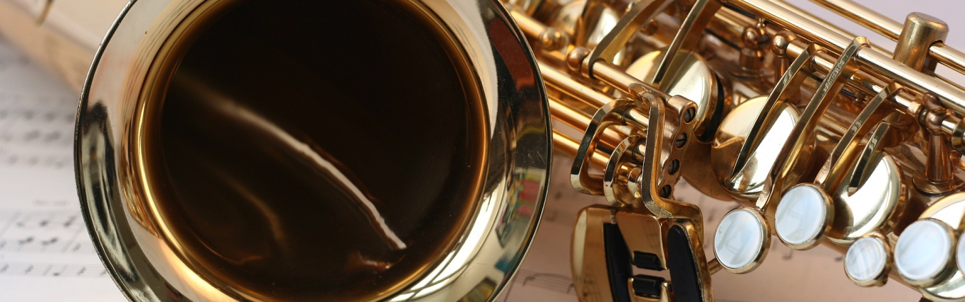 Zdjęcie saksofonu położonego na kartkach z nutami