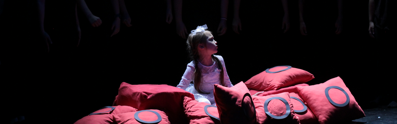 dziewczynka przebrana za księżniczkę siedzi na scenie w poduszkach