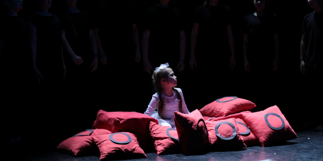 dziewczynka przebrana za księżniczkę siedzi na scenie w poduszkach