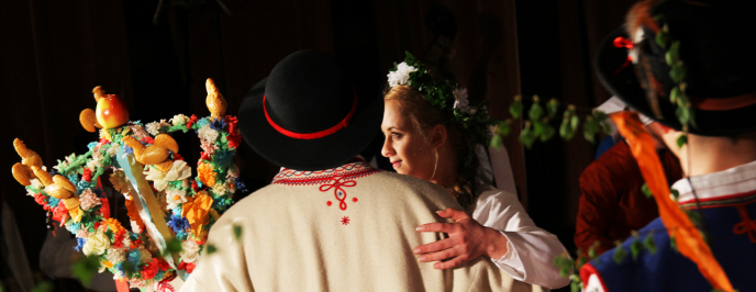Kobieta i mężczyzna w strojach regionalnych trzymają w rękach różdżkę weselną
