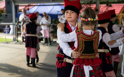 Chłopczyk i dziewczynka w strojach regionalnych z regionu krakowskiego tańczą na scenie