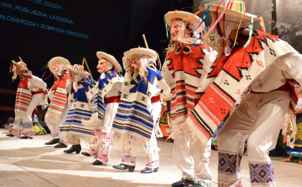 Dzieci w maskach i meksykańskich strojach ludowych tańczą na scenie