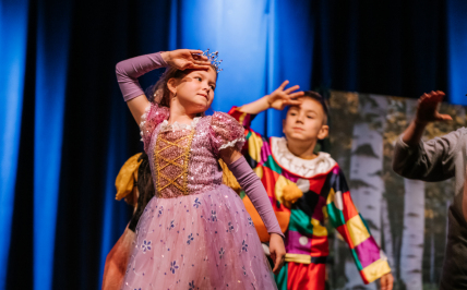 Chłopiec i dziewczynka występują na scenie w baśniowych strojach