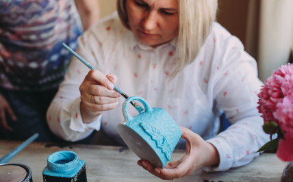 zdjęcie kobiety malującej filiżankę niebieską farbą