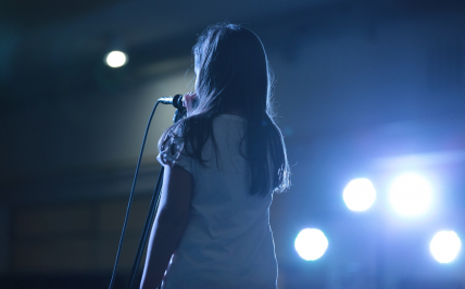 Kobieta stojąca przed mikrofonem na scenie