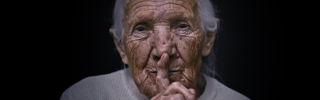 Starsza kobieta zasłania usta palcem