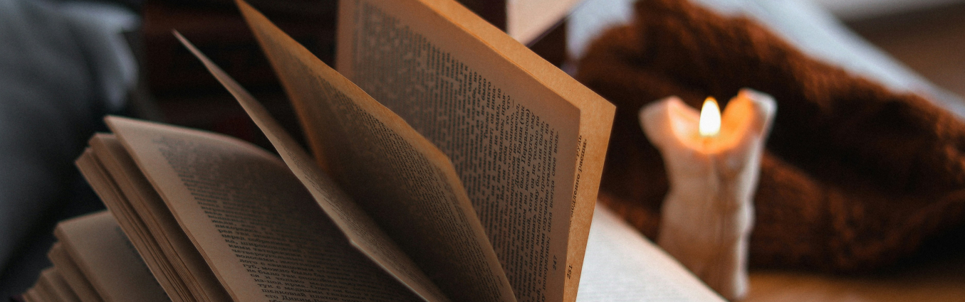 otwarta książka na stole, a obok świeca