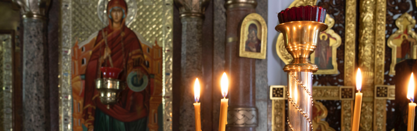 Zapalone świeczki w kościele. W tle obrazy święte.