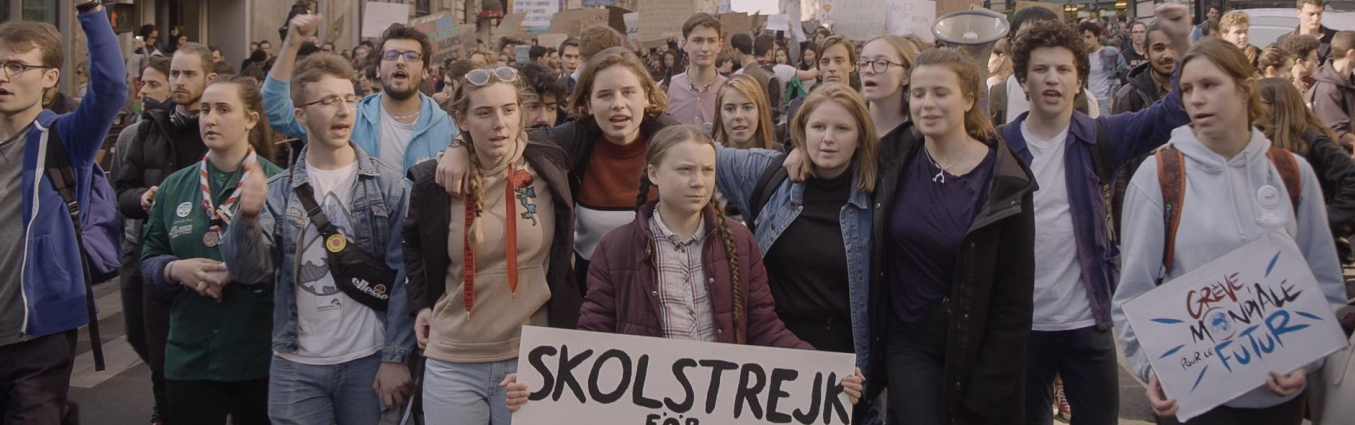 Grupa młodych osób z transparentami idąca przez miasto