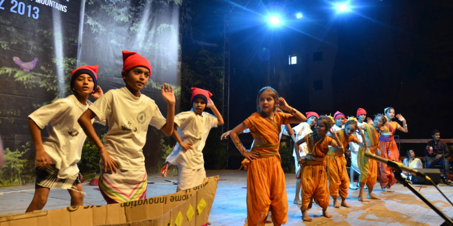 dzieci w hinduskich strojach stoją na scenie, oświetlają je światła sceniczne
