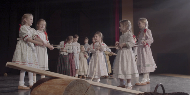 Dzieci w strojach regionalnych bawią się na scenie drewnianymi zabawkami