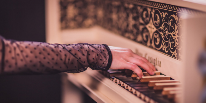 Ręce kobiety oparte o instrument klawiszowy