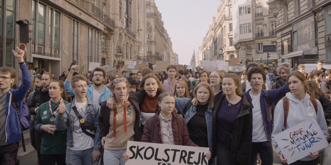Grupa młodych osób z transparentami idąca przez miasto