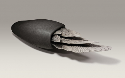 Obiekt rzeźbiarski. Długie ptasie pióra w połowie schowane do czarnej formy przypominającą torbę.