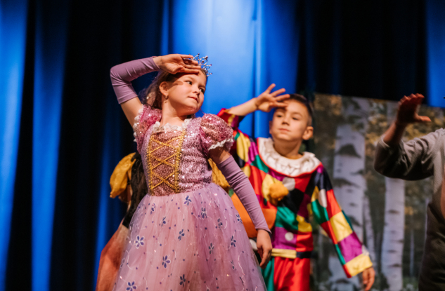 Chłopiec i dziewczynka występują na scenie w baśniowych strojach