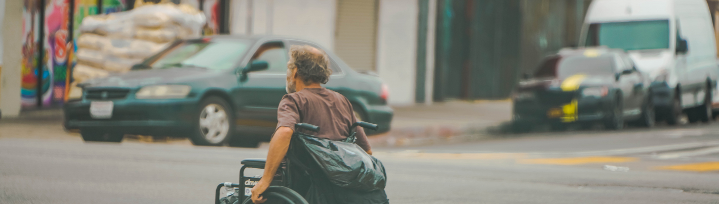 Mężczyzna na wózku inwalidzkim przejeżdża przez ulicę