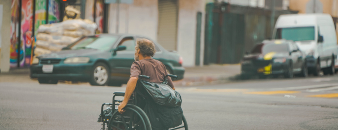 Mężczyzna na wózku inwalidzkim przejeżdża przez ulicę